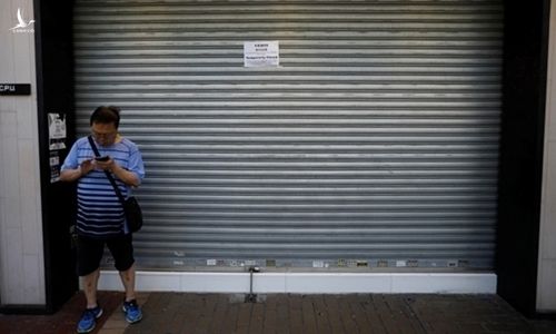 Một người qua đường đứng trước cửa tiệm dán thông báo đóng cửa vì biểu tình ở Hong Kong hôm 5/8. Ảnh: Reuters. 