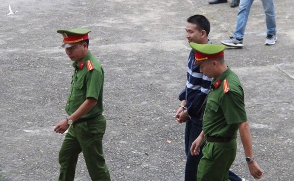 Bị tuyên án 2 năm tù, Trần Đình Sang nở nụ cười lúc rời tòa về trại giam - Ảnh 2.