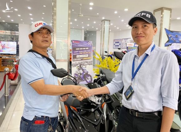 Anh Bình (bên phải) trao tặng anh Hải xe ngay tại cửa hàng bán xe máy /// Ảnh: ĐỖ TRƯỜNG