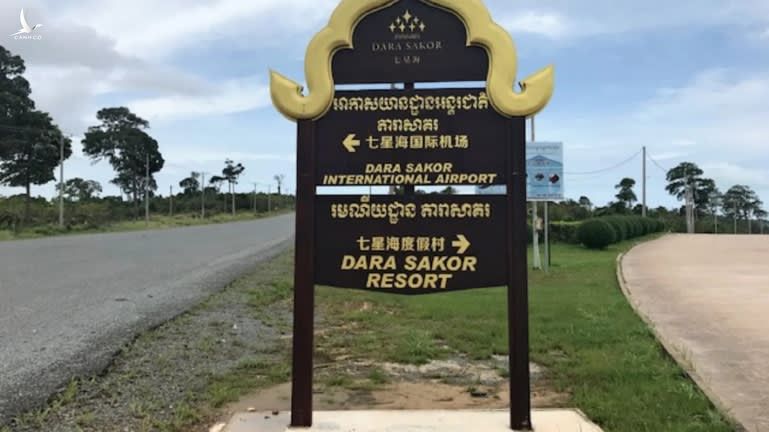 Một tấm biển hiệu chỉ đường tới sân bay có 3 loại ngôn ngữ, bao gồm tiếng Campuchia, tiếng Trung Quốc và tiếng Anh.