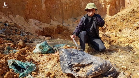 Ông Đặng Văn Tư không dám sờ tay trực tiếp vào những bao chất thải được khai quật lên từ khu đất bốc mùi thối, hắc nồng nặc /// Ảnh Lê Quân 