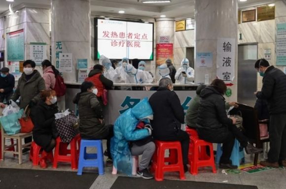 Bệnh nhân ngồi xếp hàng chờ trước một bệnh viện quá tải ở Vũ Hán /// Reuters