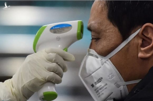 Một nhân viên y tế kiểm tra nhiệt độ người dân ở Vũ Hán /// AFP