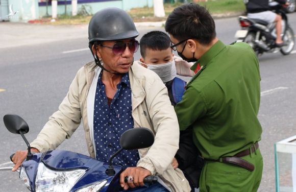 Cán bộ công an đeo khẩu trang cho người dân đi đường /// Ảnh: Hoàng Sơn