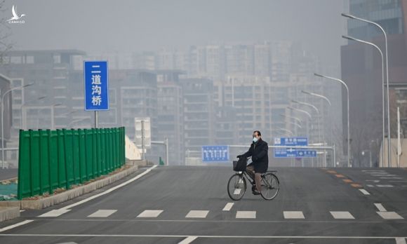 Người đàn ông đeo khẩu trang đạp xe trên phố không bóng người ở Bắc Kinh hôm 12/2. Ảnh: Washington Post.