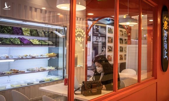 Người phụ nữ đeo khẩu trang ngồi một mình trong quán cà phê ở trung tâm thương mại Solana, Bắc Kinh hôm 12/2. Ảnh: Washington Post.