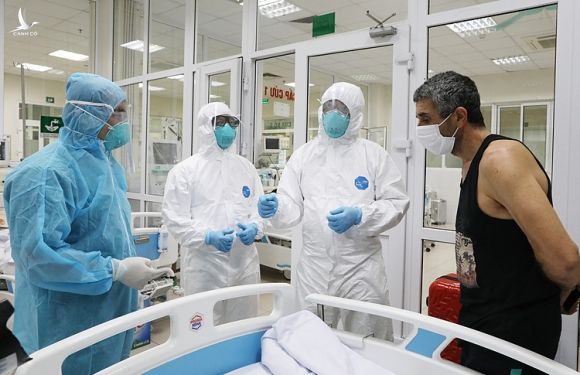 Bác sĩ Cấp trong bộ đồ bảo hộ màu xanh (ngoài cùng bên trái), đi thăm các bệnh nhân Covid-19 tại Khoa Cấp cứu chiều 24/3. Ảnh: Ngọc Thành