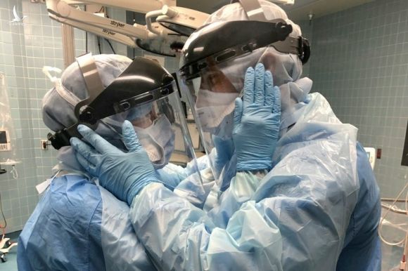 Bức ảnh được bác sĩ Nicole Hubbard chụp lại khi vợ chồng y tá đang nhìn nhau qua tấm kính bảo hộ, sau một ca phẫu thuật căng thẳng. Ảnh: Time