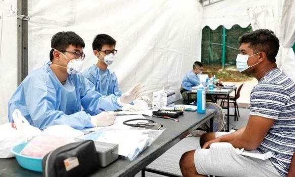 Nhân viên y tế kiểm tra một người sống trong khu ký túc xá ở Singapore hôm 7/4. Ảnh: Reuters. 
