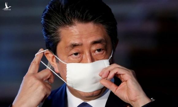 Thủ tướng Nhật Shinzo Abe điều chỉnh khẩu trang khi trò chuyện với truyền thông về phản ứng của Nhật với Covid-19 tại Tokyo hôm 6/4. Ảnh: Reuters.
