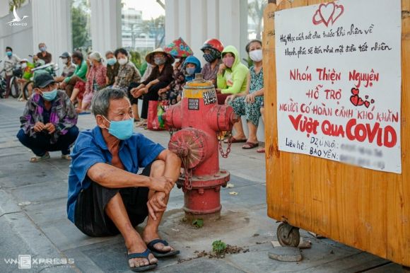 Những người dân có hoàn cảnh khó khăn ngồi chờ nhận quà từ một nhóm từ thiện trên đường Lý Chính Thắng (quận 3, TP HCM) chiều 3/4. Ảnh: Nguyệt Nhi.