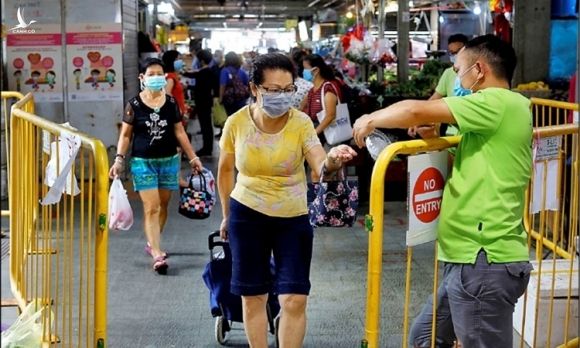 Người dân xịt khử trùng tay trước khi rời khỏi chợ ở Singapore ngày 23/4. Ảnh: Reuters.