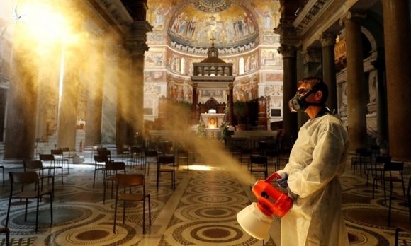 Người đàn ông khử trùng bên trong nhà thờ Trastevere Basilica ở Rome, Italy, ngày 11/5. Ảnh: Reuters.