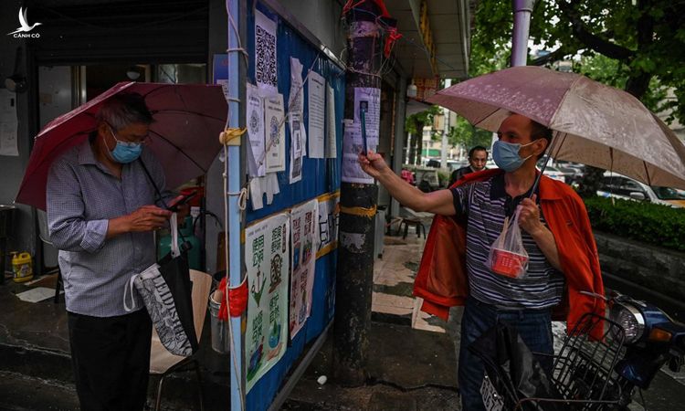 Người đàn ông dùng điện thoại chụp thông tin trên một bảng tin ở thành phố Vũ Hán, hôm 14/5. Ảnh: AFP.