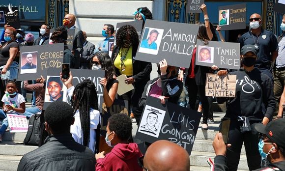 Người biểu tình giơ bảng tên và ảnh người da màu từng chết vì cảnh sát trước tòa thị chính ở San Francisco, hôm 1/6. Ảnh: NYTimes.