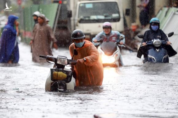 Người dân dắt xe chết máy trong cơn mưa lớn chiều 16/6 trên đường Nguyễn Hữu Cảnh (quận Bình Thạnh). Ảnh: Hữu Khoa.