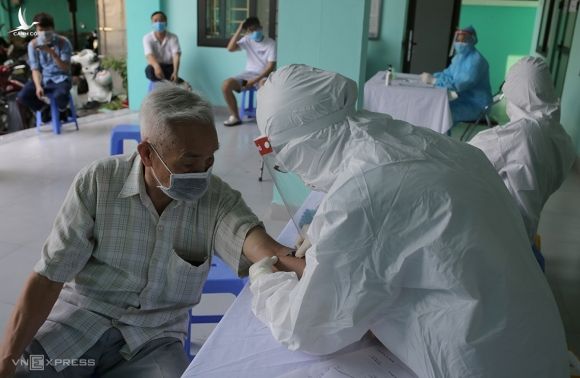 Nhân viên y tế phường Yên Hòa, quận Cầu Giấy lấy mẫu máu xét nghiệm cho người về từ Đà Nẵng ngày 30/7. Ảnh: Tất Định.