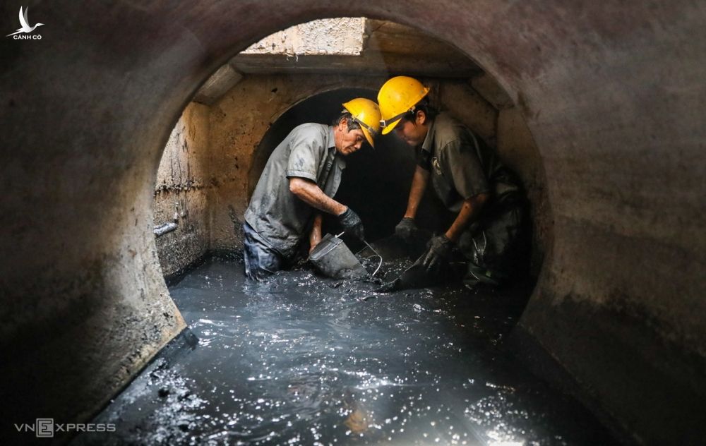 Cha con ông Nguyễn Phú Hộ (53 tuổi) móc bùn thải tại một cống thoát nước trên đường Nguyễn Ảnh Thủ, quận 12, TP HCM, ngày 14/8. Ảnh: Quỳnh Trần