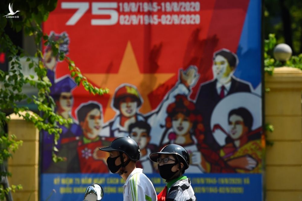 Hai thanh niên đi qua áp phích chào mừng ngày Quốc khánh hôm 1/9. Ảnh: AFP.