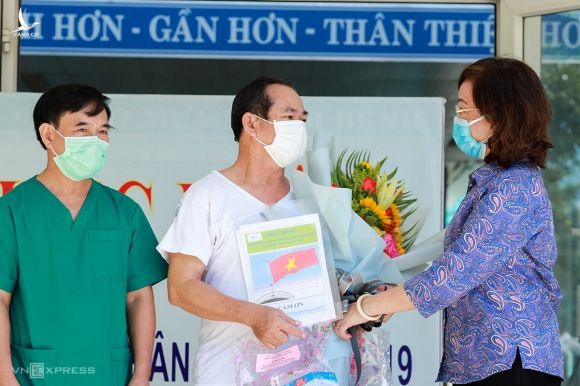 Bệnh nhân 936 (áo trắng) nhận hoa chúc mừng từ Giám đốc Sở Y tế Ngô Thị Kim Yến. Ảnh: Nguyễn Đông.
