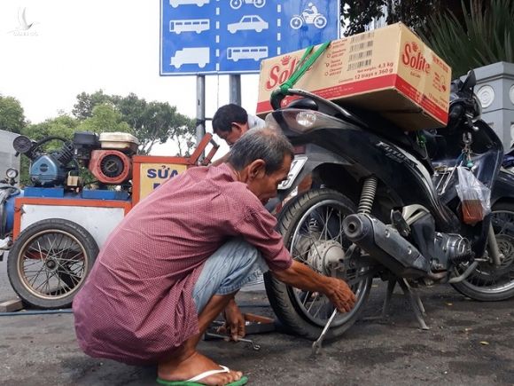 Người đàn ông lớn tuổi phá ruột xe tại điểm vá xe ở góc đường Lê Duẩn - Tôn Đức Thắng (Q.1) /// ẢNH: TRẦN TIẾN
