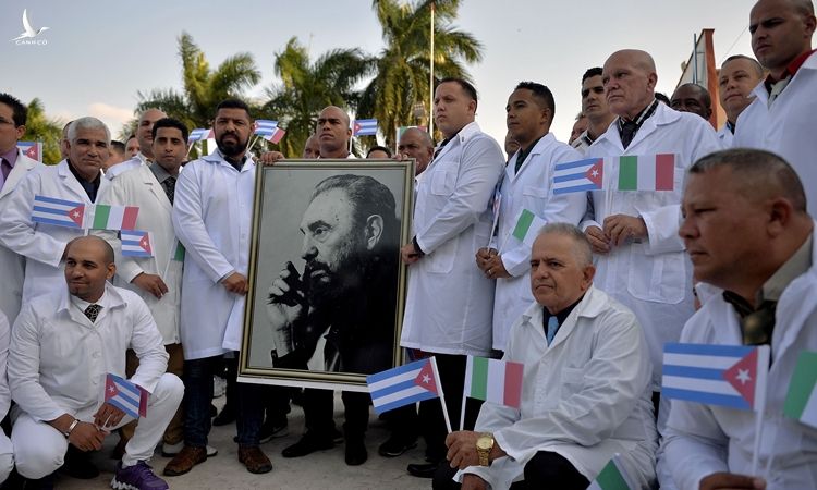 Đoàn bác sĩ quốc tế Cuba Henry Reeve cầm ảnh chân dung cố lãnh tụ Fidel Castro trước khi lên đường tới Italy hôm 21/3. Ảnh: AFP.