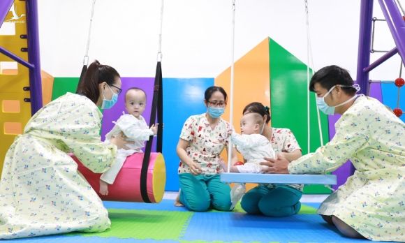 Hai bé vừa chơi xích đu, vừa tập phản xạ cầm nắm, tự chống đỡ, cân bằng cơ thể. Ảnh: Hữu Khoa.