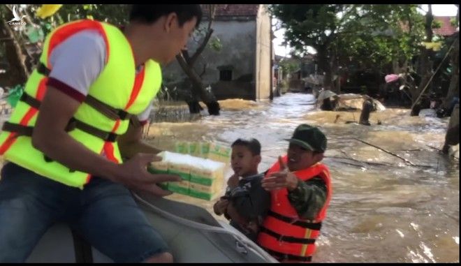 Anh Hào nhảy xuống dòng nước lũ ôm em bé đang bơi đến thuyền của mình khiến nhiều người xúc động /// ẢNH: CHỤP MÀN HÌNH