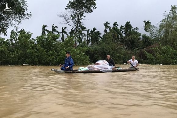 Người dân xã Hương Toàn (thị xã Hương Trà) chèo thuyền giữa nước lũ nhận mì tôm, nhu yếu phẩm cứu trợ. Ảnh: Hoàng Táo