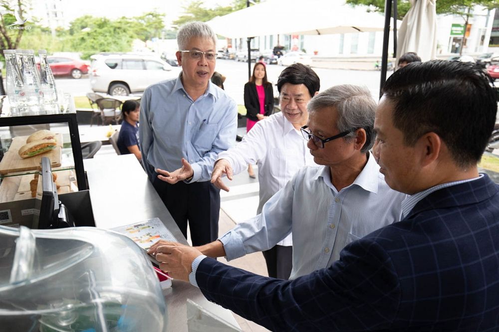 Ông Nguyễn Đức Kiên, Tổ trưởng Tổ tư vấn kinh tế của Thủ tướng Chính phủ (ngoài cùng bên trái) cùng các thành viên tổ tư vấn và lãnh đạo MoMo trải nghiệm thanh toán bằng ví điện tử tại một cửa hàng đồ uống tại quận 7, TP HCM chiều 12/10. Ảnh: Thy Nhật