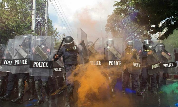 Cảnh sát Thái Lan bị người biểu tình ném bom khói màu tại thủ đô Bangkok hôm 17/11. Ảnh: AFP.