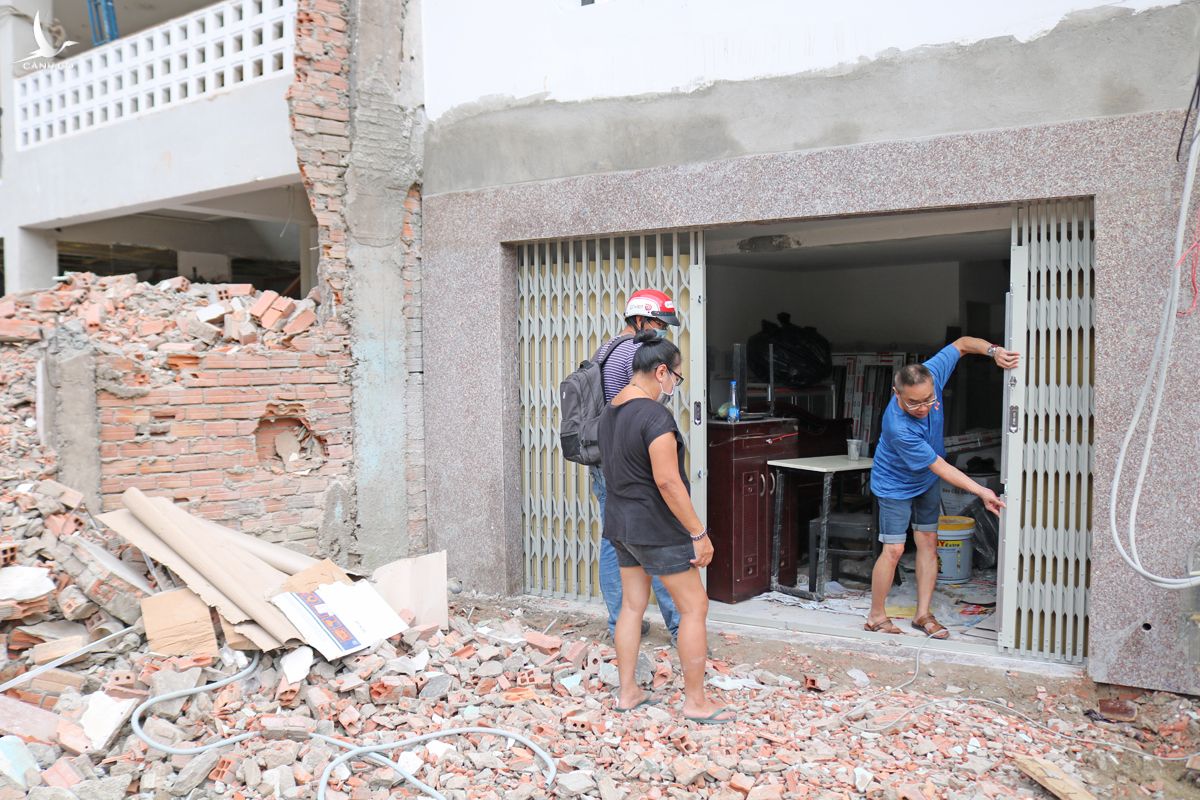 Anh Tuấn Anh (áo xanh) cùng gia đình đang sửa lại nhà sau khi bàn giao lại phần đất phía trước, chiều 27/11. Ảnh: Gia Minh.