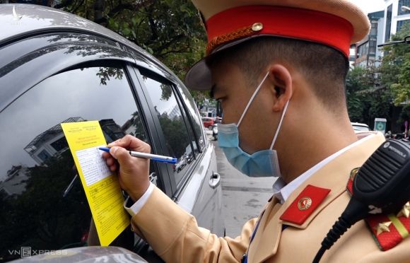 Tổ công tác thuộc Đội CSGT số 6 dán phiếu thông báo phạt nguội trên xe ôtô dừng đỗ trên phố Duy Tân, Cầu Giấy ngày 15/12. Ảnh: Văn Lộc