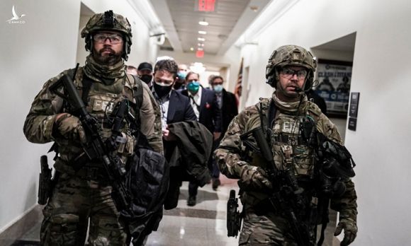 Lực lượng an ninh tại Đồi Capitol đưa các nghị sĩ trở lại phòng họp sau cuộc hỗn loạn hôm 6/1. Ảnh: New York Times.