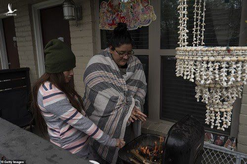 Karla Perez và Esperanza Gonzalez (Houson, bang Texas) sưởi ấm bên bếp nướng vì mất điện. Ảnh: Getty