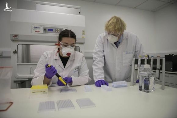 Thủ tướng Anh Boris Johnson (phải) cùng kỹ thuật viên kiểm soát chất lượng vaccine tại phòng thí nghiệm ở Scotland, ngày 28/1. Ảnh: AP