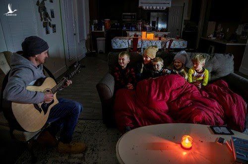 Một người cha ở Pflugerville (bang Texas) đàn hát cho các con nghe trong ánh nến lập lòe. Ảnh: Reuters