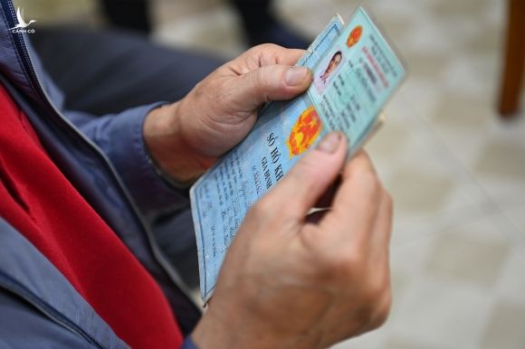 Một người dân cầm chứng minh thư và hộ khẩu giấy đi làm thẻ căn cước công dân gắn chip, ngày 9/3. Ảnh: Giang Huy