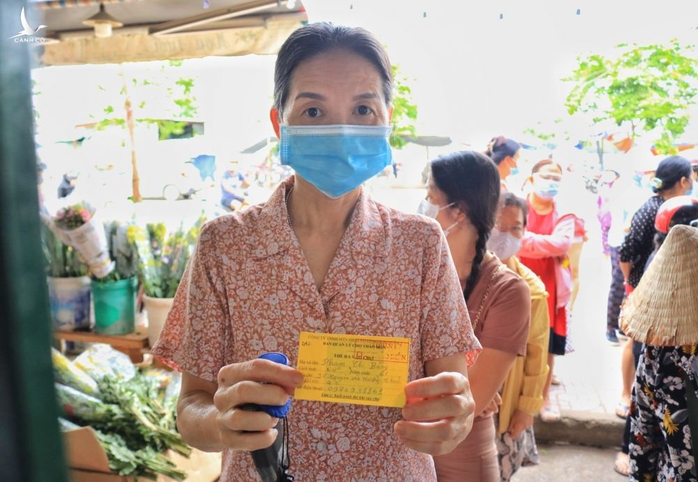 Bà Phạm Thị Bằng (61 tuổi, ngụ TP.Thủ Đức) cầm thẻ ra vào, xếp hàng chờ được vào trong mua thực phẩm /// ẢNH: CAO AN BIÊN