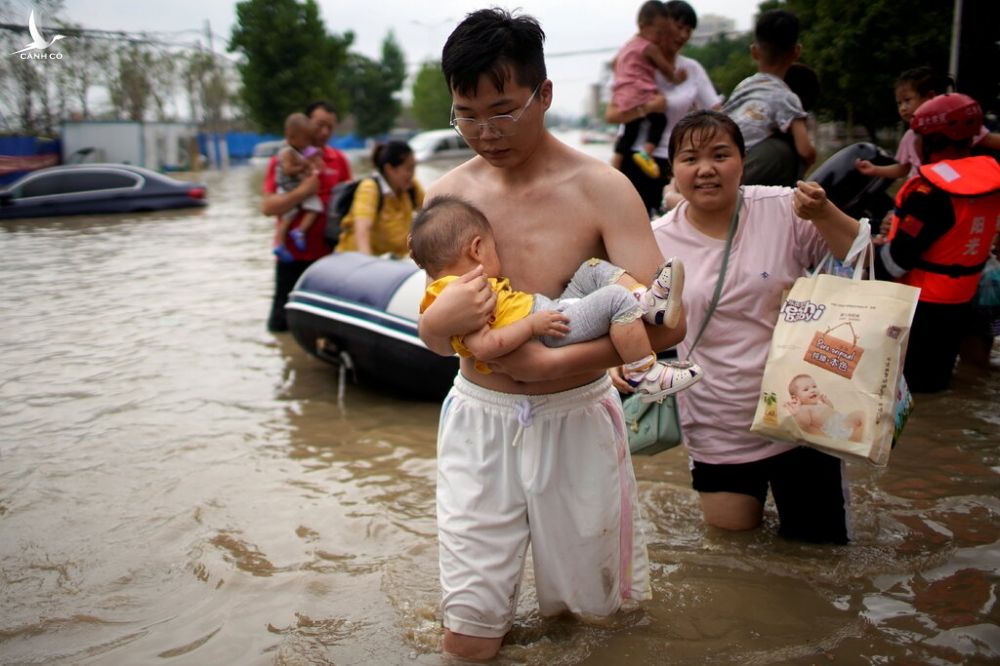 Người dân Trịnh Châu lội qua vùng ngập vào ngày 22/7, được lực lượng cứu hộ hướng dẫn đến nơi an toàn. Ảnh: Reuters.