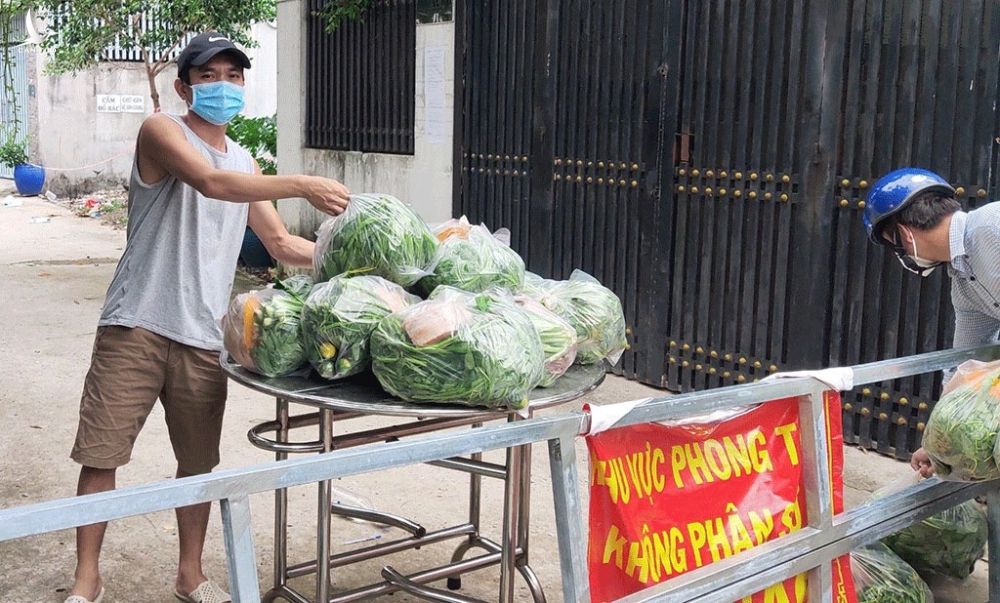 Người dân trong khu vực phong tỏa ở H.Hóc Môn (TP.HCM) nhận quà hỗ trợ là rau xanh từ các nhà hảo tâm ẢNH: S.Đ