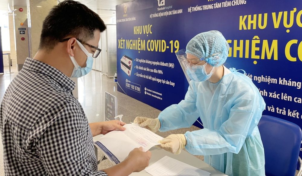 Nhân viên y tế trả giấy kết quả xét nghiệm Covid-19 cho hành khách test nhanh kháng nguyên tại sân bay. Ảnh: