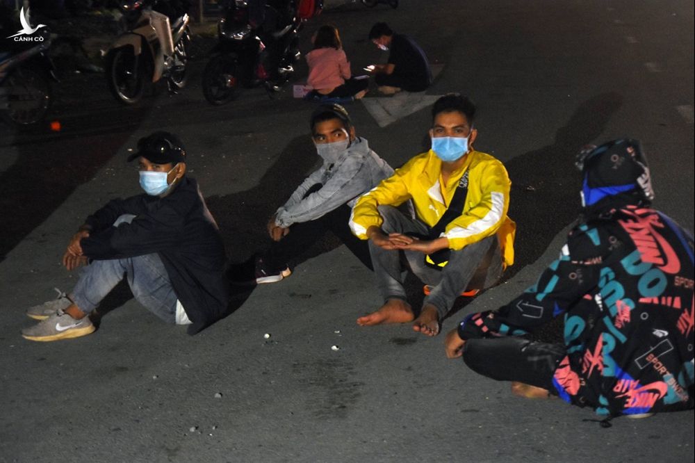 Công nhân ngồi vật vã bên quốc lộ 1K tại chốt kiểm soát TP Dĩ An. Ảnh: Thái Hà