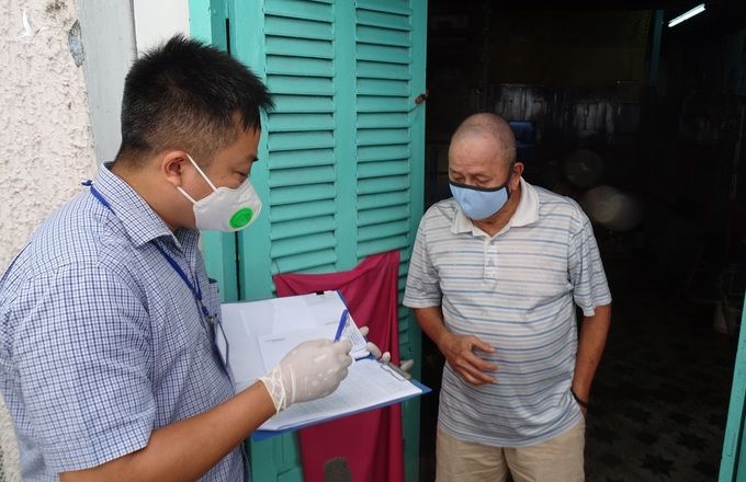 Ông Vương Chí Tài (phải), 72 tuổi, làm nghề bán vé số, ở phường Đa Kao, quận 1, nhận tiền hỗ trợ đợt một, trưa 12/7. Ảnh: Hà An