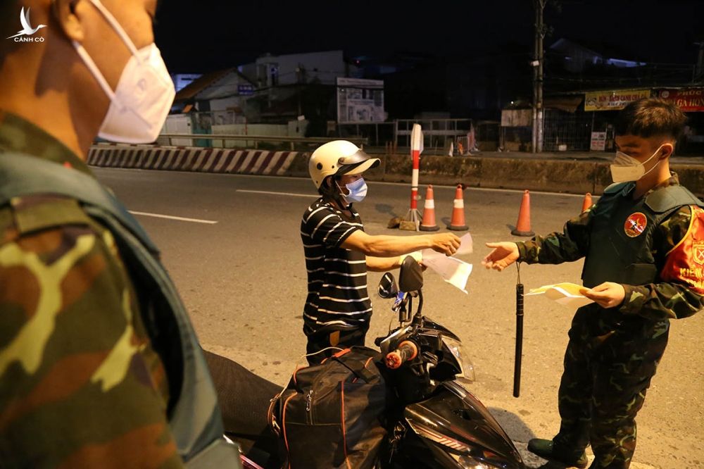 Người đi xe máy bị kiểm tra giấy tờ và yêu cầu khai báo qua phần mềm tại chốt kiểm soát cầu Vĩnh Bình, TP Thủ Đức, tối 12/8. Ảnh: Đình Văn