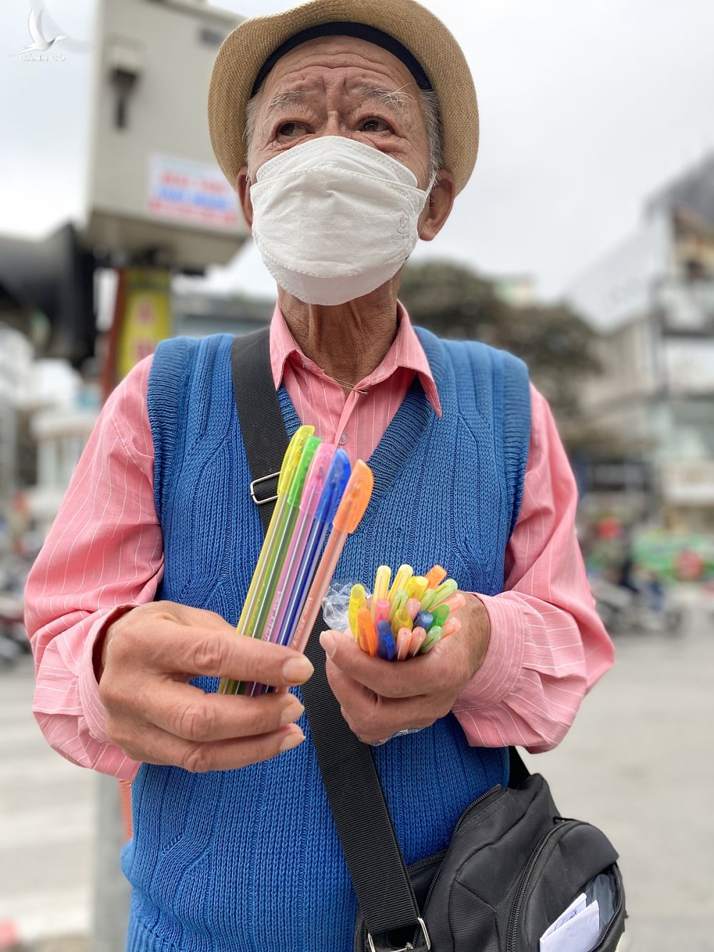 Ông Diệp đang đứng bán bút bi tại khu vực dải phân cách cắm cột đèn giao thông đường Khâm Thiên, trưa 8/1. Ảnh: Quỳnh Nguyễn