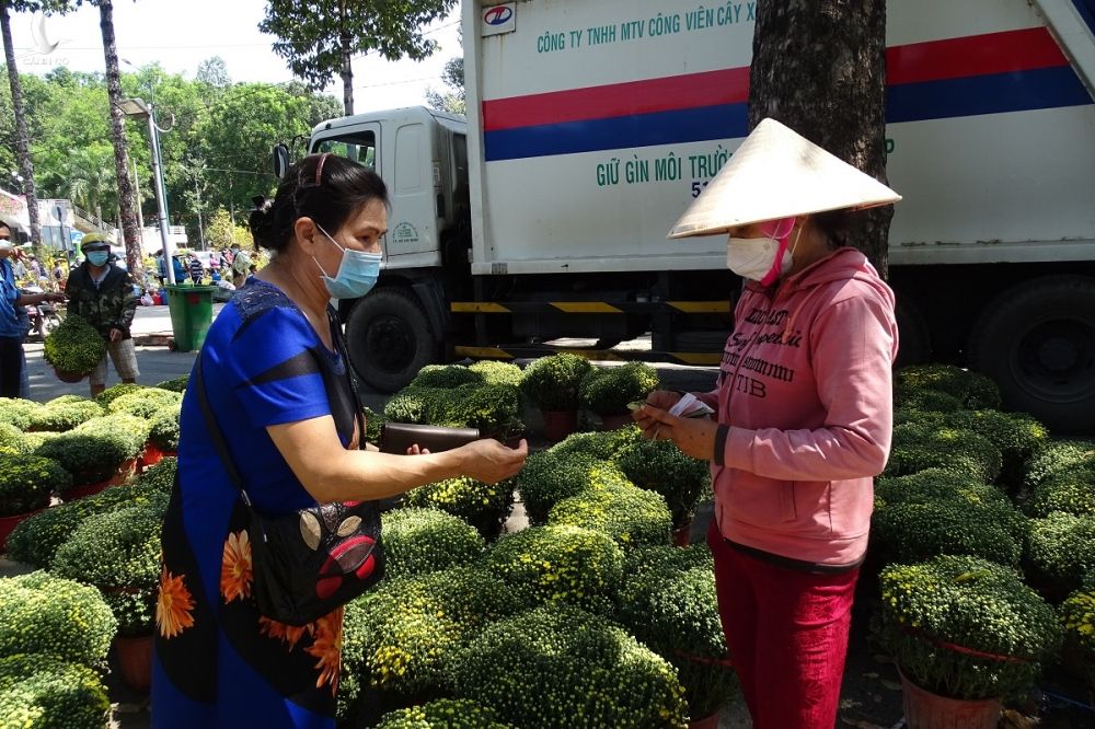 Một người dân (trái) tới mua hoa ủng hộ gia đình anh Thiện. Ảnh: Hà An