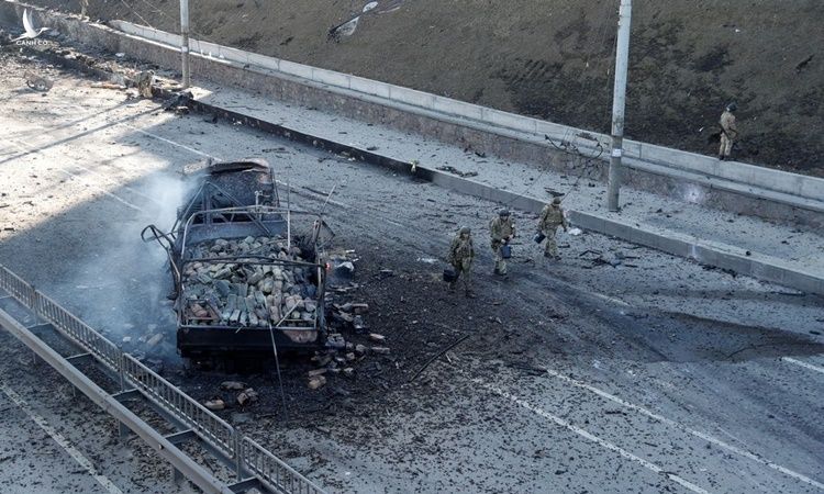 Các binh sĩ Ukraine đi qua một chiếc xe bị phá hủy sau giao tranh ở ngoại ô Kiev ngày 26/2. Ảnh: Reuters.