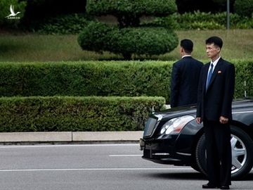 Hai vệ sĩ đứng gác bên cạnh một chiếc xe limousine của lãnh đạo Triều Tiên. Ảnh: AFP.