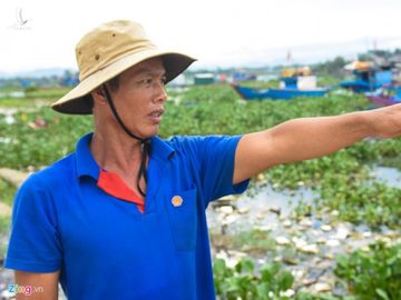 Ngư dân Phạm Cận chỉ tay về phía hàng trăm chiếc tàu công suất lớn nằm bờ ở "cửa ngõ" dẫn về làng chài xã Nghĩa An.  